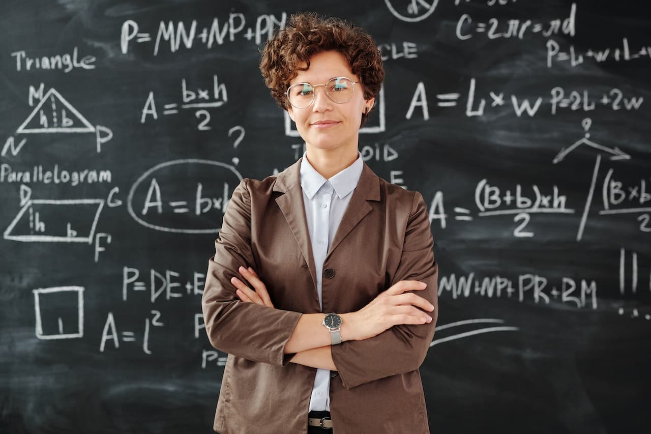 Professoressa di matematica di fronte un alavagna con delle formule, che si trovano nel formulario di matematica.