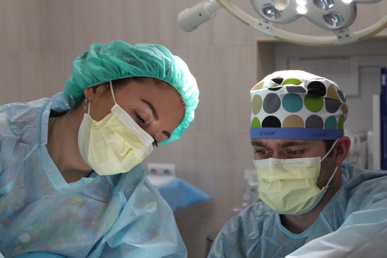 Due medici con mascherina sul volto in sala operatoria. L'immagine rappresenta il settore professionale in cui si pone la domanda "quanto guadagna un neurochirurgo".