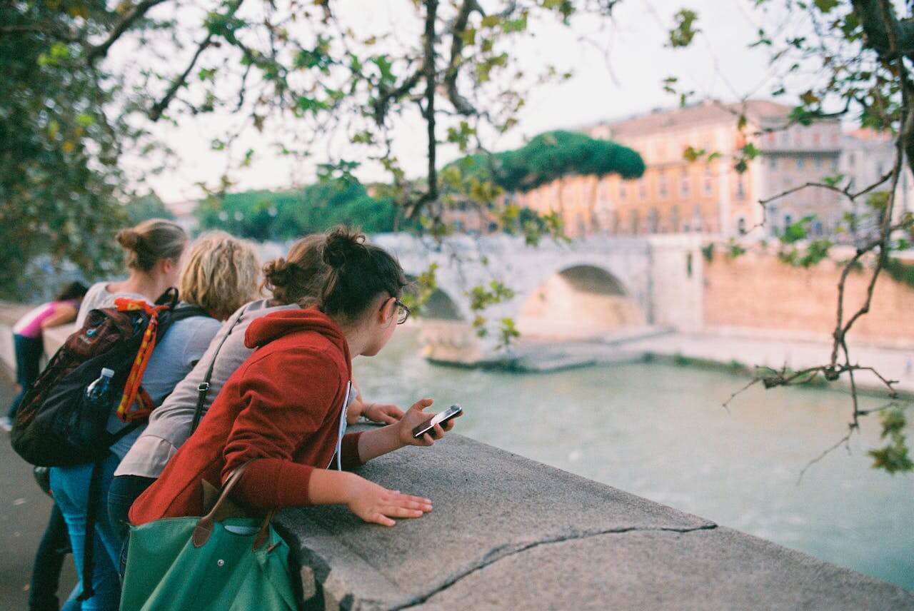 Persone che guardano il fiume Tevere di Roma da un cornicione affacciato sul letto d'acqua.