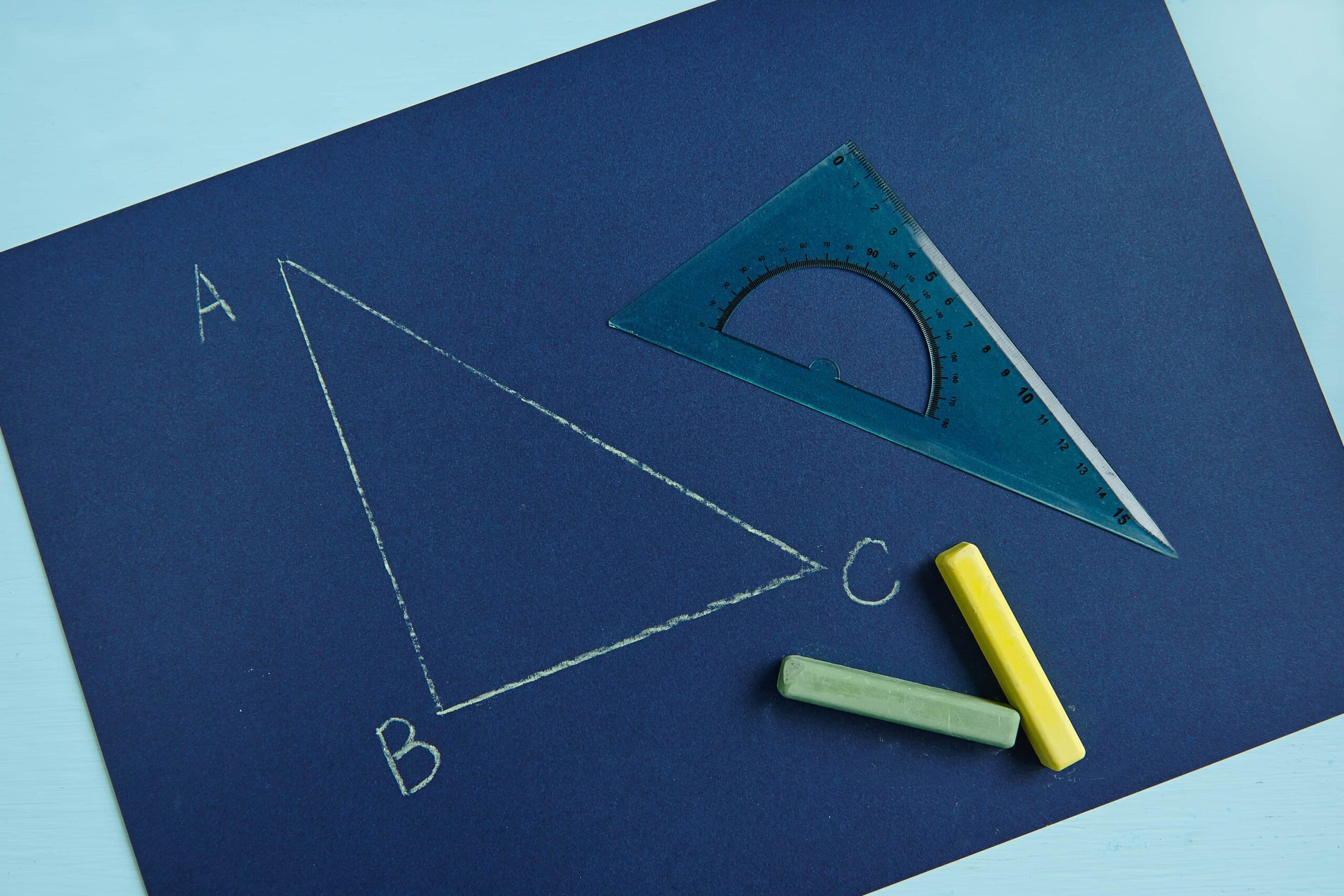 Cartoncino blu scuro con sopra il disegno di un triangolo rettangolo realizzato con una squadra e due gessetti colorati.